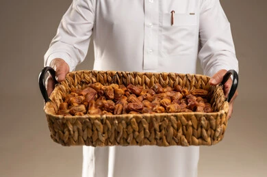 رجل سعودي يحمل سلة من التمور المجففة