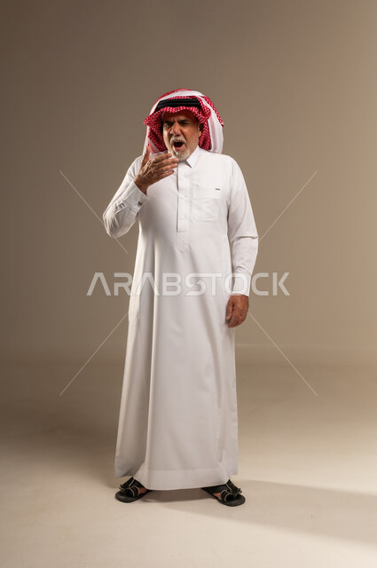 رجل سعودي مسن بالثوب التقليدي يتثاءب في الاستوديو