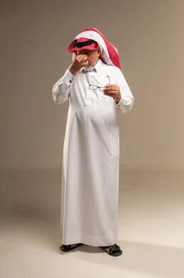 رجل سعودي مسن متعب يفرك عينيه في الاستوديو