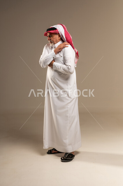 Elderly Saudi Man Holding Shoulder in Pain
