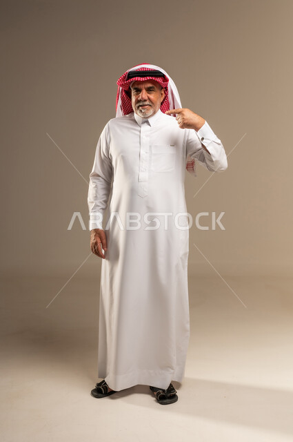 رجل سعودي مسن بالثوب التقليدي يشير بإصبعه