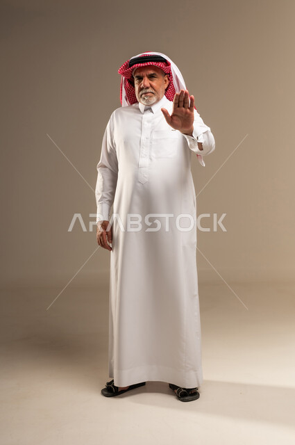 رجل سعودي مسن يشير بعلامة التوقف بالزي التقليدي