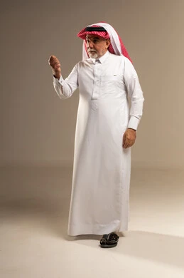 رجل سعودي مسن بالزي التقليدي يشير بيده في استوديو