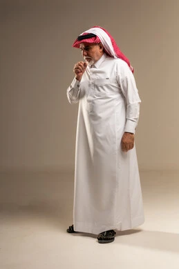 رجل سعودي مسن يسعل بالثوب التقليدي في استوديو