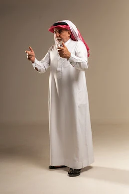 رجل سعودي مسن يشير باليد بالثوب التقليدي في الاستوديو