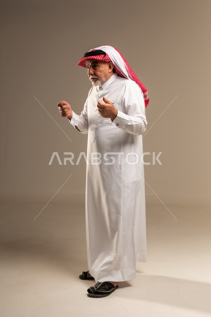 رجل سعودي مسن بالثوب التقليدي مع إيماءات في الاستوديو