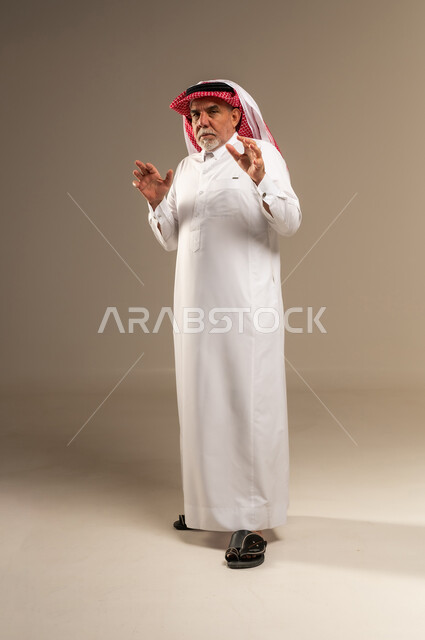 رجل سعودي مسن يرتدي الثوب التقليدي ويقوم بإيماءات يدوية