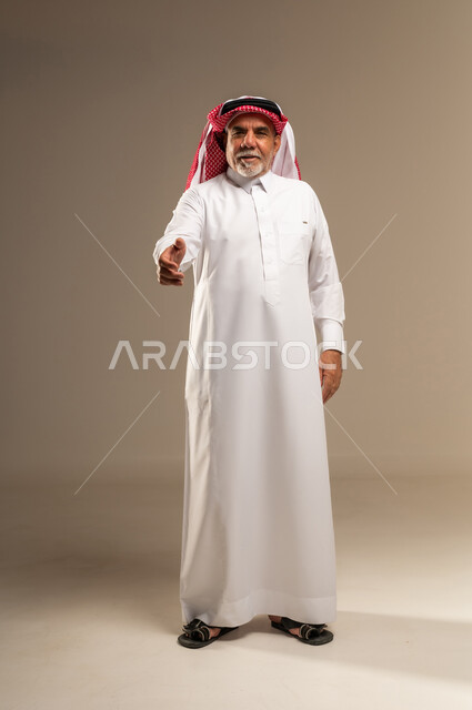 رجل سعودي مسن يصافح في استوديو بخلفية محايدة