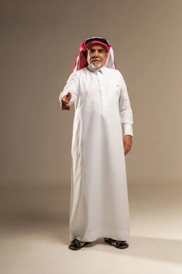 رجل سعودي مسن يصافح في استوديو بخلفية محايدة