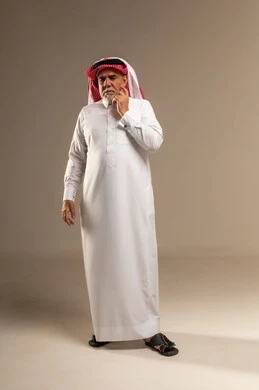 رجل سعودي مسن بالثوب يفكر أمام خلفية محايدة