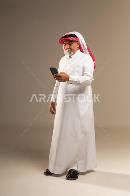 Elderly Saudi Man Using Smartphone in Studio Background