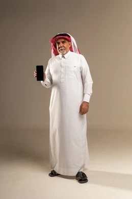 رجل سعودي مسن يحمل هاتف ذكي في الاستوديو