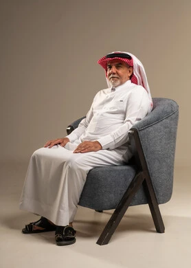 رجل سعودي مسن بالزي التقليدي يجلس على كرسي