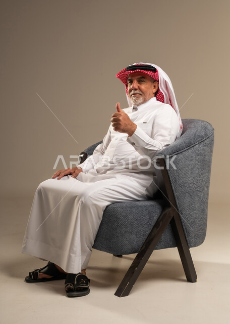 رجل سعودي مسن يشير بالإبهام للأعلى بالزي التقليدي