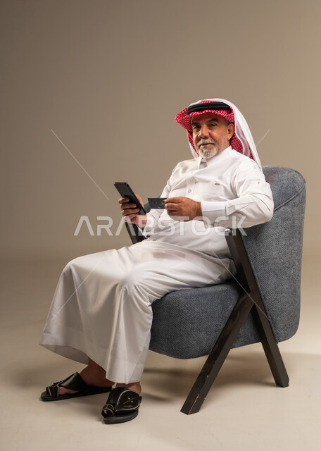 رجل سعودي مسن يستخدم بطاقة الائتمان والهاتف الذكي