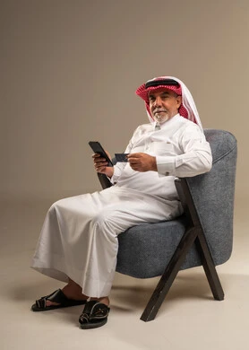 رجل سعودي مسن يستخدم بطاقة الائتمان والهاتف الذكي