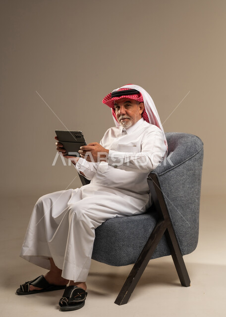 رجل سعودي مسن يستخدم جهاز لوحي في الاستوديو
