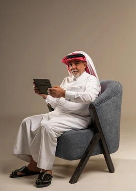 رجل سعودي مسن يستخدم جهاز لوحي في الاستوديو