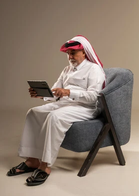 رجل سعودي مسن يستخدم جهاز لوحي في الاستوديو
