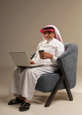 رجل سعودي يستخدم المحمول ويحمل كوب قهوة