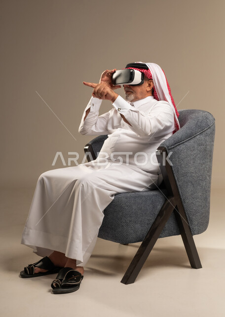 Elderly Saudi Man Wearing VR Headset in Studio Armchair