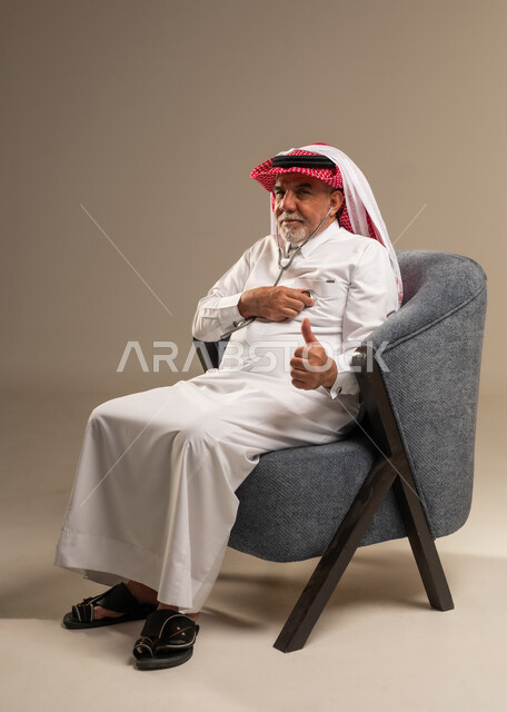 رجل سعودي مسن مع سماعة طبية يرفع إبهامه