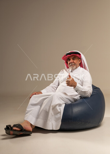 Senior Saudi Man on Beanbag Giving Thumbs Up