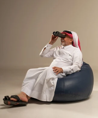 رجل سعودي بالزي التقليدي يستخدم المنظار