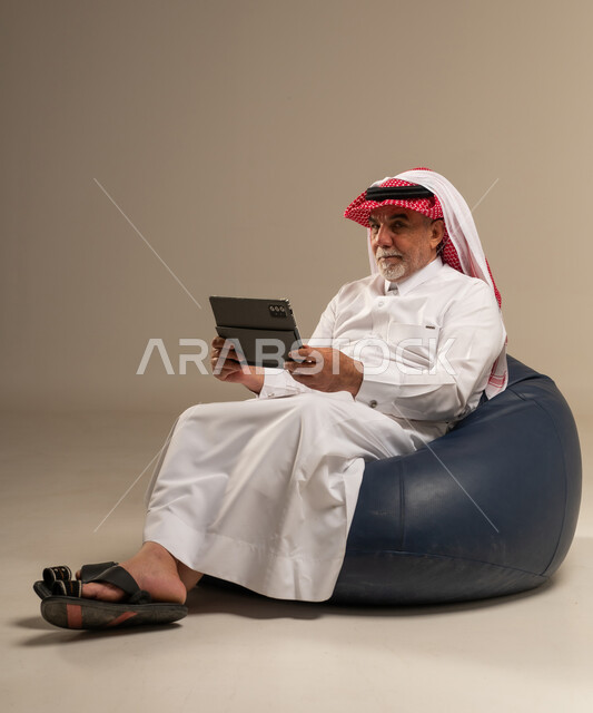 Saudi Man Using Tablet Sitting on Bean Bag in Studio