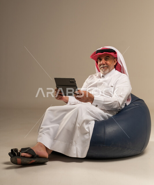 رجل سعودي مسن مع جهاز لوحي على بين باج
