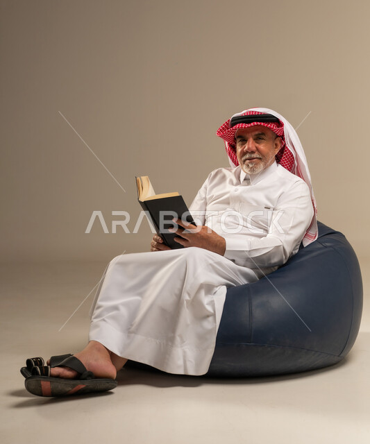 رجل سعودي مسن يقرأ كتاباً على مقعد محشو