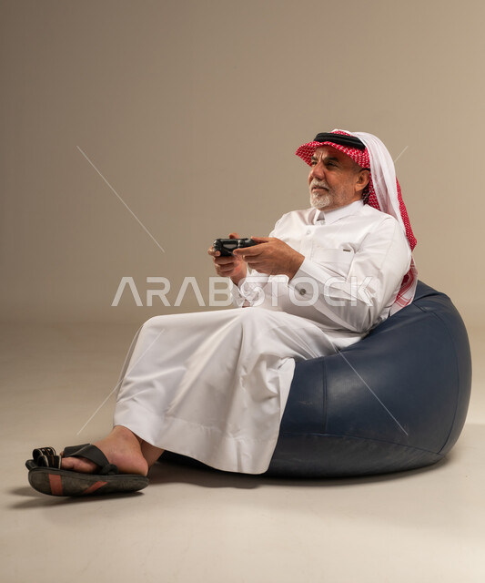 رجل سعودي مسن يلعب ألعاب الفيديو بالزي التقليدي
