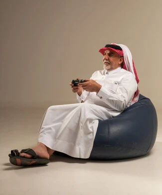 Senior Saudi Man Playing Video Games in Traditional Dress