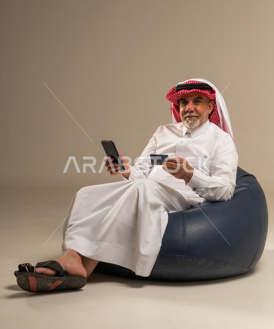 رجل سعودي مسن يستخدم الهاتف وبطاقة الائتمان