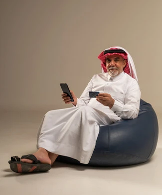 رجل سعودي مسن يستخدم الهاتف وبطاقة الائتمان
