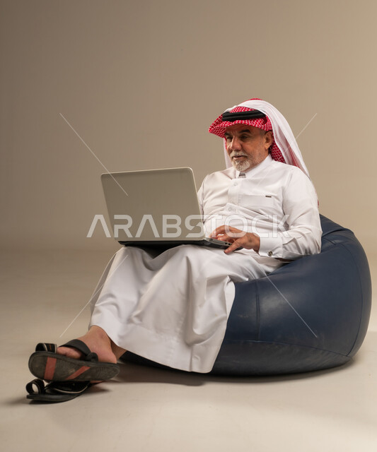 رجل سعودي مسن يستخدم كمبيوتر محمول على بين باج