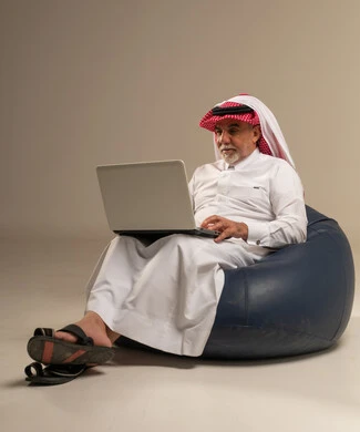 رجل سعودي مسن يستخدم كمبيوتر محمول على بين باج