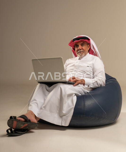 Senior Saudi Man Using Laptop in Studio Setting