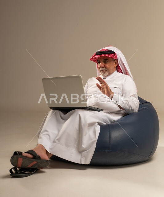 رجل سعودي مسن يستخدم الحاسوب على مقعد استرخاء