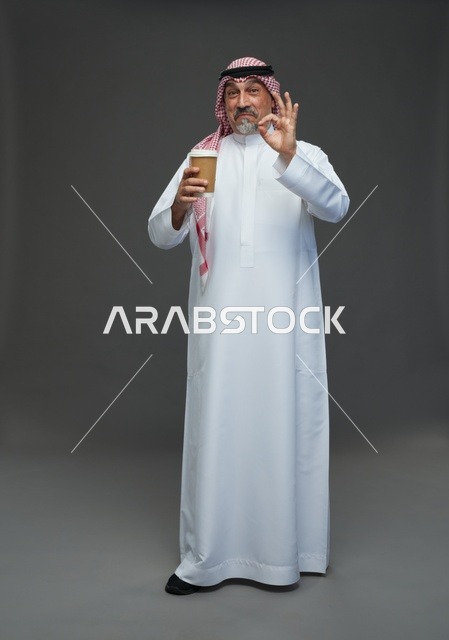 An elderly Arab Saudi Gulf man wearing a white thobe and a shemagh, holding a cup of coffee, with various gestures and signs, full body, gray background.