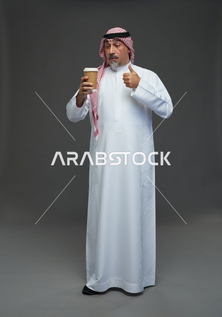 رجل  عربي سعودي خليجي مسن يرتدي الزي الثوب الابيض والشماغ ويحمل فنجان قهوة,  ايماءات واشارات مختلفه , كامل الجسم, خلفيه رماديه