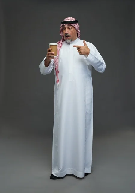 An elderly Arab Saudi Gulf man wearing a white thobe and a shemagh, holding a cup of coffee, with various gestures and signs, full body, gray background.