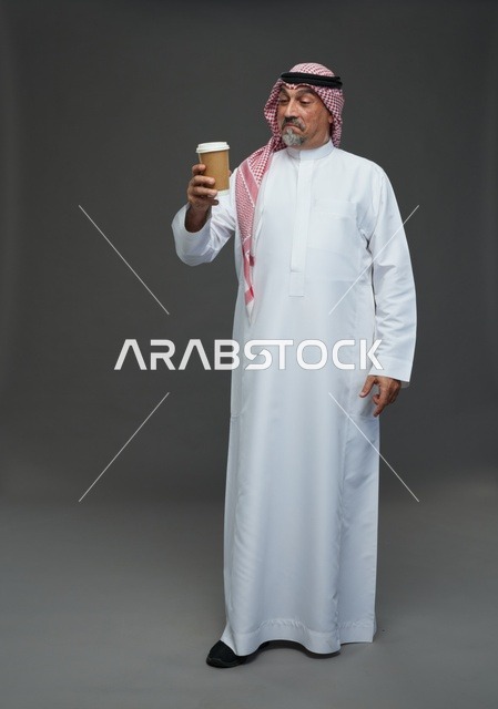 رجل  عربي سعودي خليجي مسن يرتدي الزي الثوب الابيض والشماغ ويحمل فنجان قهوة,  ايماءات واشارات مختلفه , كامل الجسم, خلفيه رماديه