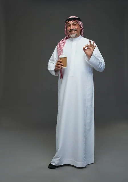 An elderly Arab Saudi Gulf man wearing a white thobe and a shemagh, holding a cup of coffee, with various gestures and signs, full body, gray background.