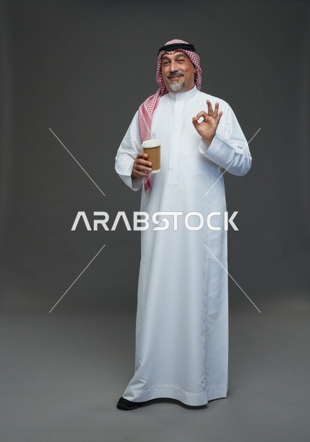 An elderly Arab Saudi Gulf man wearing a white thobe and a shemagh, holding a cup of coffee, with various gestures and signs, full body, gray background.