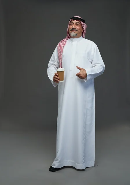 رجل  عربي سعودي خليجي مسن يرتدي الزي الثوب الابيض والشماغ ويحمل فنجان قهوة,  ايماءات واشارات مختلفه , كامل الجسم, خلفيه رماديه