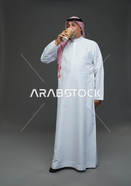 رجل  عربي سعودي خليجي مسن يرتدي الزي الثوب الابيض والشماغ ويحمل فنجان قهوة,  ايماءات واشارات مختلفه , كامل الجسم, خلفيه رماديه