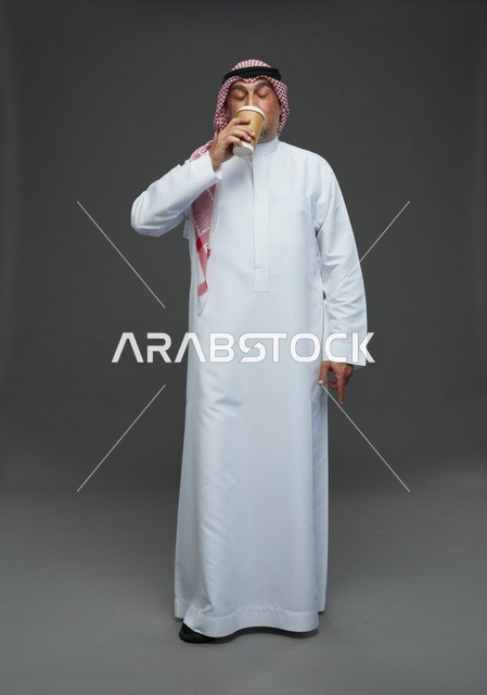 رجل  عربي سعودي خليجي مسن يرتدي الزي الثوب الابيض والشماغ ويحمل فنجان قهوة,  ايماءات واشارات مختلفه , كامل الجسم, خلفيه رماديه