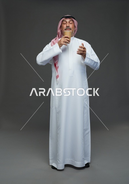 رجل  عربي سعودي خليجي مسن يرتدي الزي الثوب الابيض والشماغ ويحمل فنجان قهوة,  ايماءات واشارات مختلفه , كامل الجسم, خلفيه رماديه