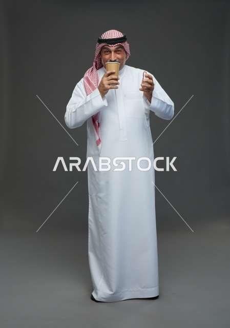 رجل  عربي سعودي خليجي مسن يرتدي الزي الثوب الابيض والشماغ ويحمل فنجان قهوة,  ايماءات واشارات مختلفه , كامل الجسم, خلفيه رماديه
